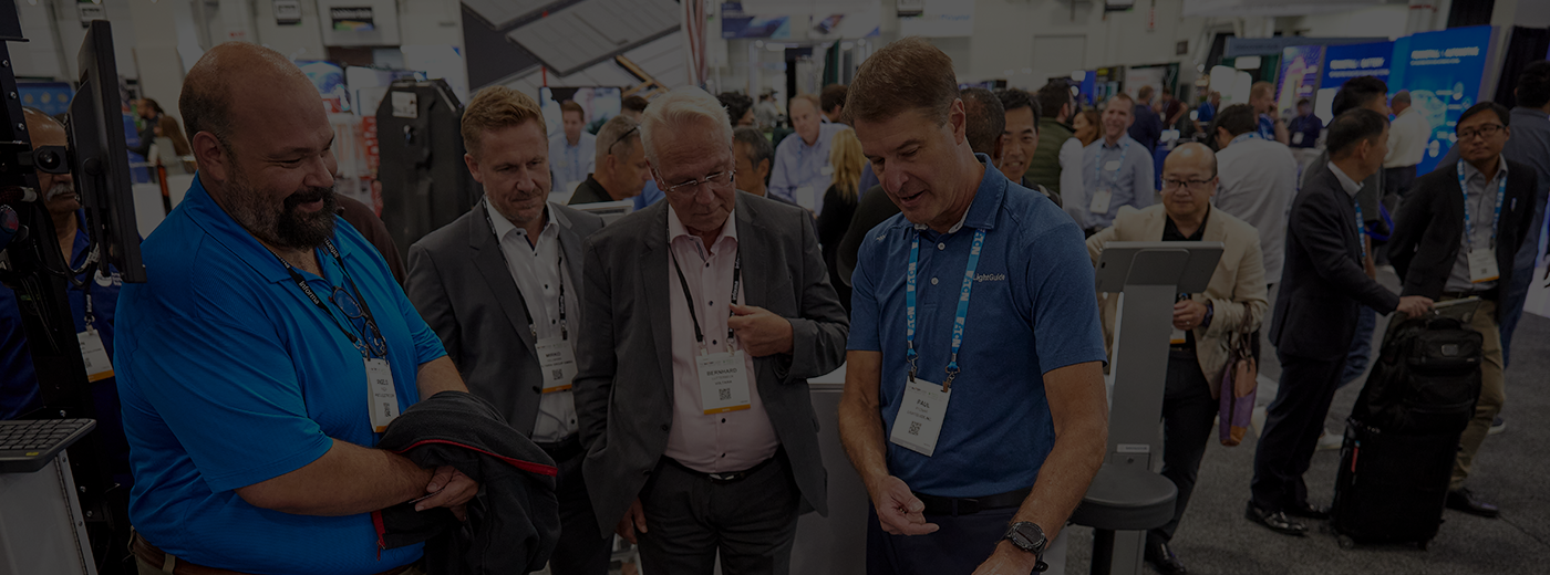 An exhibitor is explain his product to 3 attendees