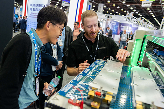 Two men focused on a computer display at an event, sharing insights and observations