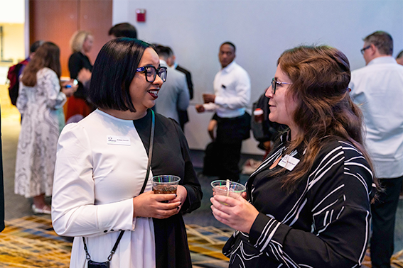  Two women engaged in conversation at a social event, sharing ideas and enjoying the atmosphere around them.