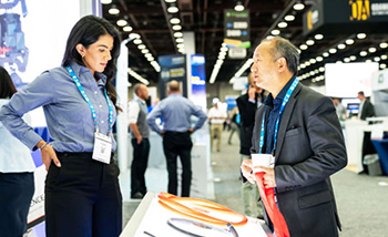 A man and woman are positioned in front of a display at an event, discussing the items on display.