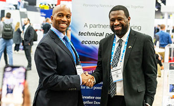 Two men engaged in a handshake at an event, representing a professional connection.