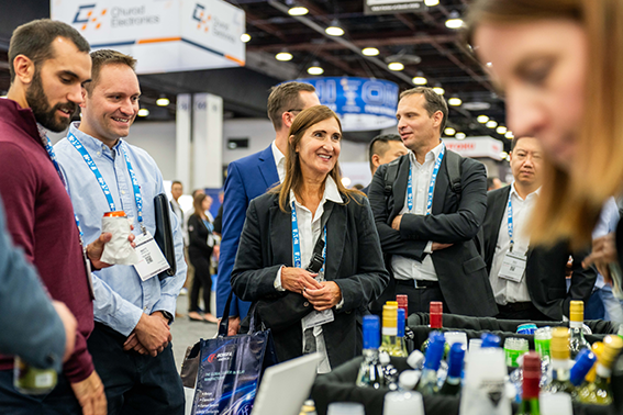  People interacting at a trade show, showcasing an array of alcohol bottles on display.